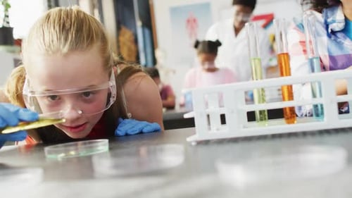 Diverse female teacher and happy schoolchildren having science class in school lab