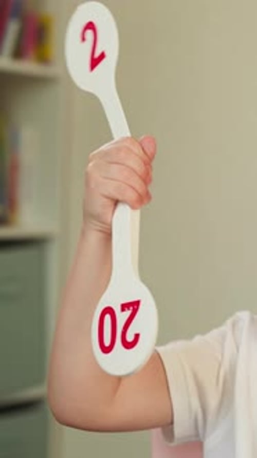 Child Holding Twenty-Two Paddle in Bright Room