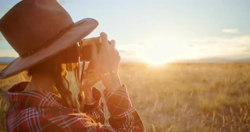 Photographer Taking Pictures with Vintage Camera in a Field at Sunset