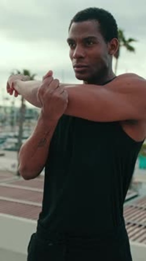 Vertical video, Young Man Stretching Before a Workout by the Marina