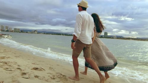 Young caucasian couple walking holding hands on a beautiful australian beach