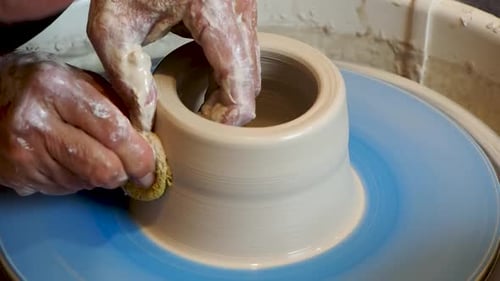 Close up of the potter's hand shaping and molding clay on a turning wheel .