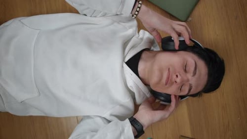 A Relaxed Young Individual Enjoys Listening to Music While Themselves at Home Comfortably