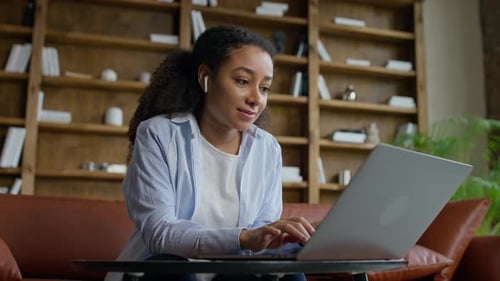 Woman Works on Laptop at Home with Bookshelves
