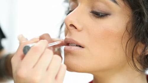 Woman Having Lip Gloss Applied by Makeup Artist