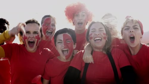 Football fans celebrate in the crowd watching the game at sport stadium. Soccer supporters