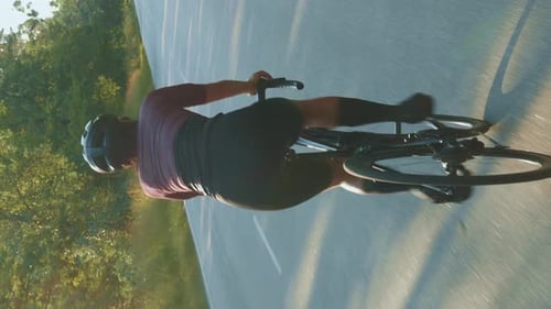 Woman riding bicycle at sunset. Vertical video