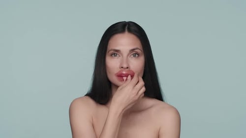 Portrait of a Seminude Woman with Hyaluronic Patches on Her Lips in the Studio on a Blue Background