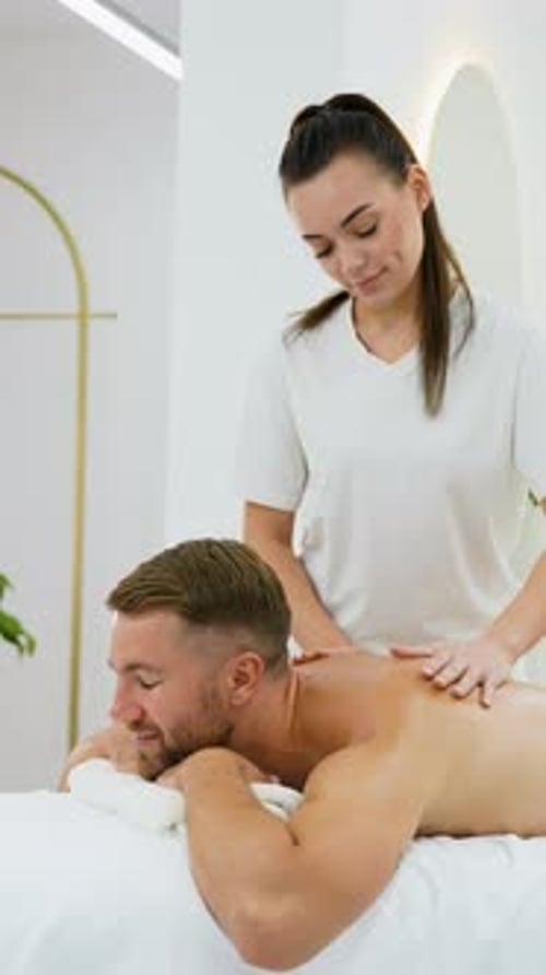 Female Therapist Giving Neck Massage to Male Client in Spa
