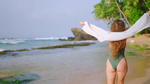 Curlyhaired Woman in Green Bikini Walks on Sandy Beach Waves White Shawl By Clear Sea Invites