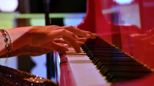 Close-up of an elderly woman playing a red piano
