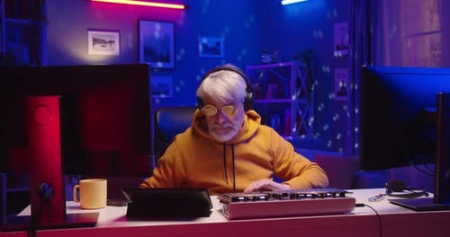 Happy Funny Stylish Old Male DJ Working at Home Studio Making Music on Mixer Console Streaming