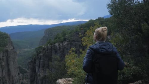 Hübsche Touristenfrau mit Aktentasche steht abends auf einer Klippe oder einem Canyon