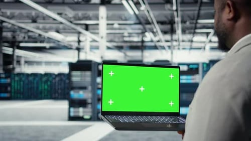 Imagem aproximada do técnico usando laptop de tela verde no data center