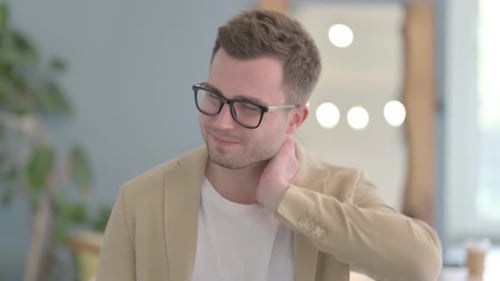 Man Rubbing Neck in Discomfort Indoors