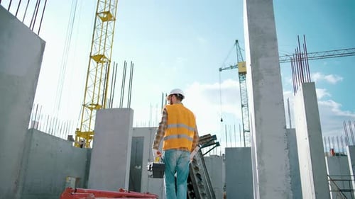Construction Worker on Site Surveys Structure Blueprint