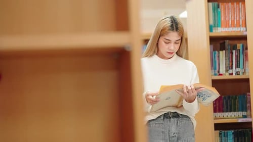 A beautiful Asian female student researching books at the university library.