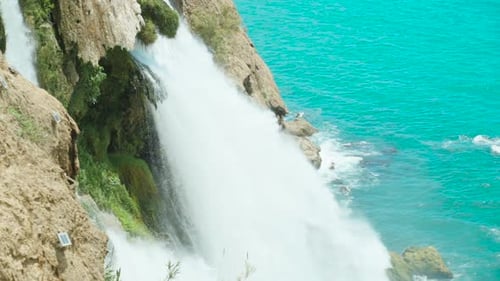 The waterfall flows into the sea. Blue water. Slow mo