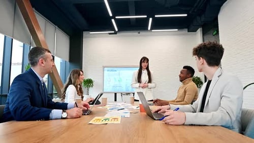 Female team leader at business meeting in an office, discussing business affairs with workers using