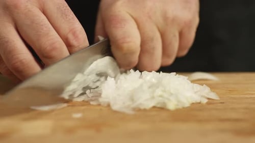 Hands Dicing Onion on Wooden Cutting Board