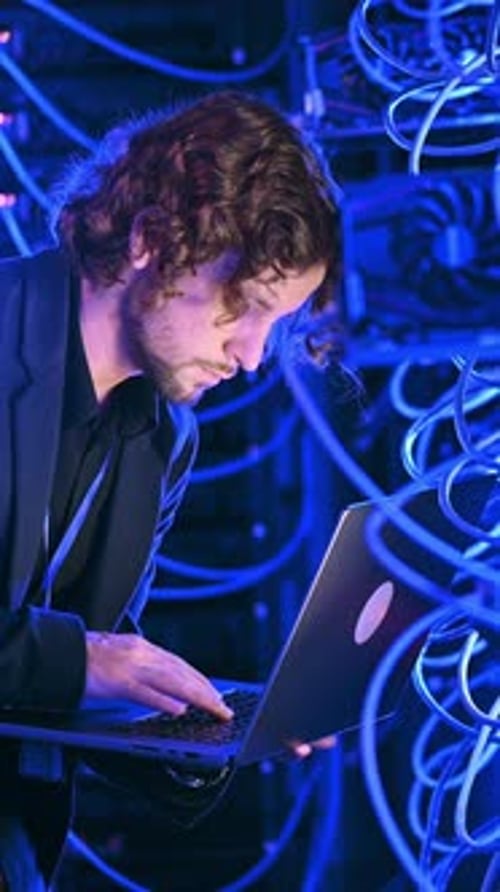 Young Adult Working on Laptop in Server Room