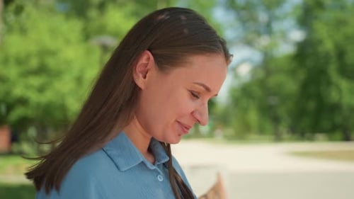 Lady Seated in Park with Book and Serene Environment Female Individual Engrossed in Paperback Novel