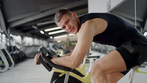 Young Man Intensely Training on Gym Biking Equipment