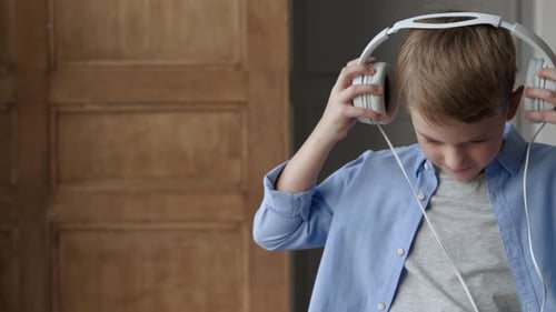 Young boy listening to music on headphones indoors