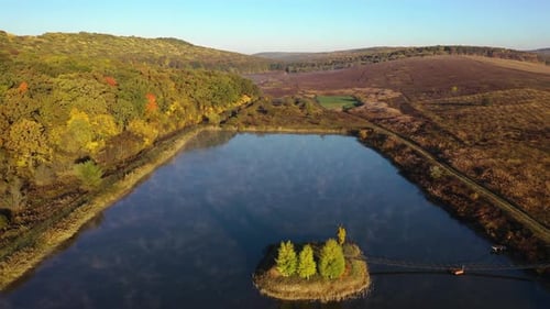 pedestal aerial shot of an artificial island with wooden bridge during sunrise, autumn, fall