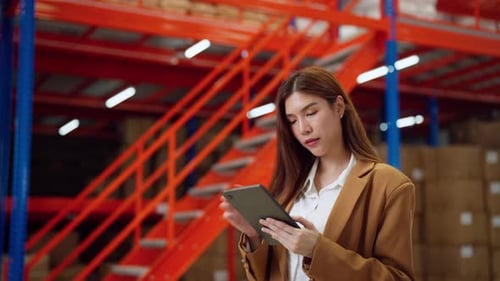 Female warehouse manager in business attire using a tablet