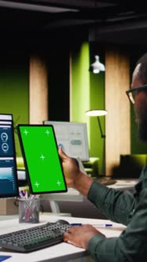 Vertical Video Green Screen on Tablet Next to Young Black Businessman Reviewing Data