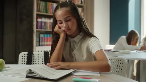 Bored Schoolgirl Caucasian Girl Kid Child Pupil Read Book in School Library Sad Tired Learner
