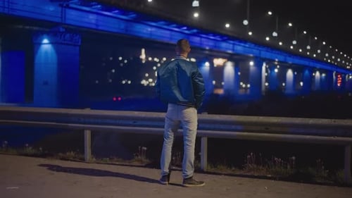 Quiet Roadside Scene with Man Watching Bright Bridge Lights Individual Stands Beside Guardrail