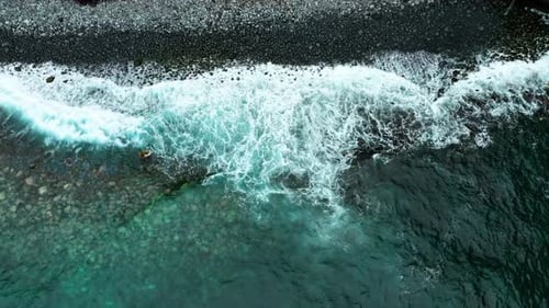 Waves Ocean Crashing Against a Ground of Black Rough Reef Rock Shallow Seashore The Rocks Eroded By