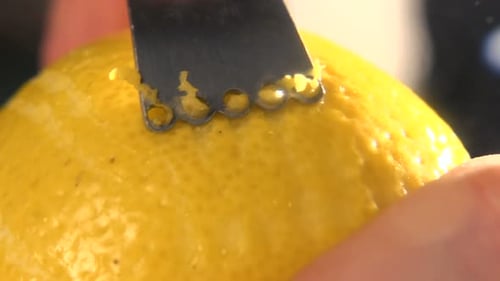 Restaurant chef zesting fresh lemon peel in slow motion kitchen close up