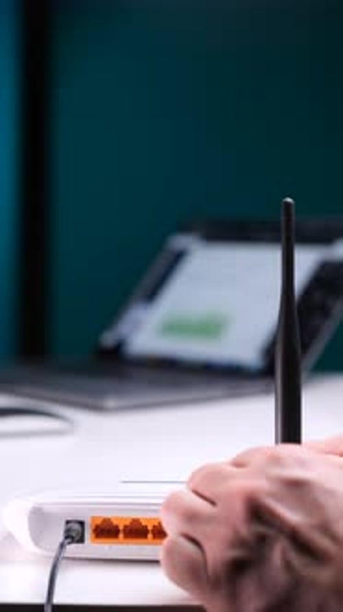 Hands Adjusting Router Antenna in Office