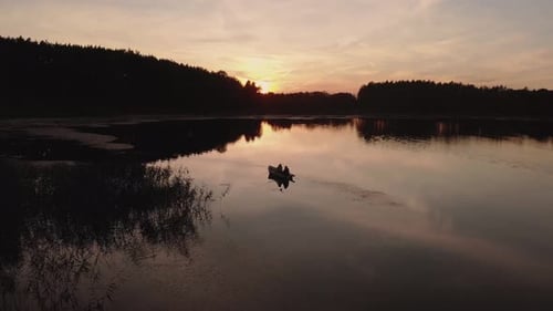 Couple Sitting On The Boat Enjoying The Quiet And Serene Lake During A Golden Hour On Sunset In Rogo
