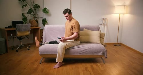 Man with Prosthetic Leg Using Phone on Couch