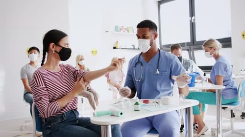 Nurse giving vaccine shot to seated woman