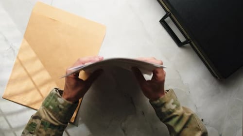 Camouflage Arms Putting Classified Documents into Envelope