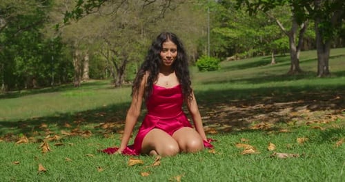 A young Latina girl, in a striking red dress, basks in the ambiance of a tropical Caribbean park.