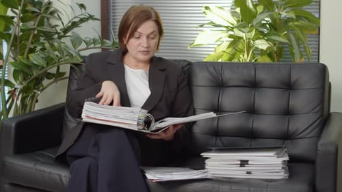 Businesswoman Placing Documents Before Leaving Office Sofa