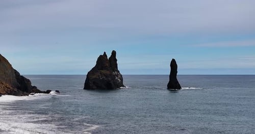 Zwei majestätische Berge erheben sich aus dem Meer, ihre Präsenz spiegelt sich in den sanften Wellen wider, die leise von