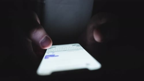 Person Typing on Smartphone in Dark Environment