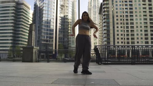 Young woman with brown hair dancing performing around big buildings in London slow motion