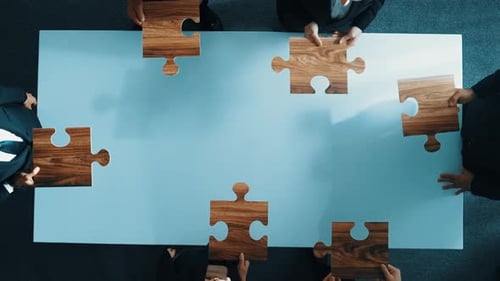 Business Team Assembling Jigsaw Puzzle From Above
