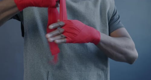 Closeup of Male African American MMA Fighter Wrapping Hands Then Hitting Fists on Purple Color