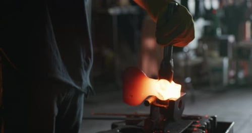 Blacksmith Shaping Hot Metal with Hammer in Workshop