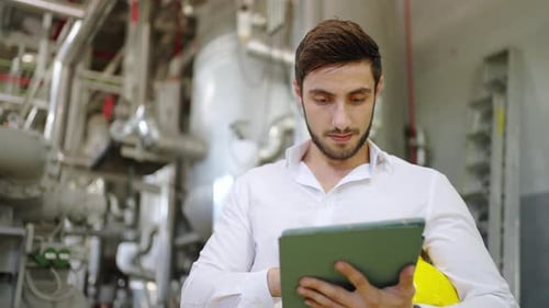 4K Male engineer working on digital tablet at factory site.
