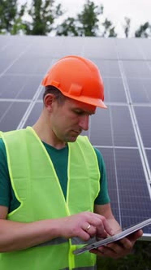 An Engineer Configures and Checks the Operation of Solar Panels on a Tablet